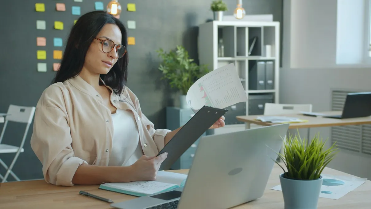 Une analyste à son bureau, un document et son ordinateur